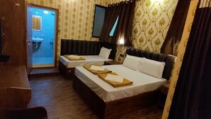 Ein Hotelzimmer mit zwei Betten, einem durchgehenden Türspalt erkennbaren Badezimmer und einem an der Wand befestigten Fernseher.