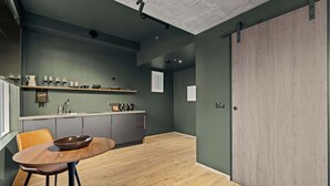 A modern kitchen with a wooden dining table and chairs, a built-in shelf with kitchenware, and a large sliding door. - Aurora Nooks - Economy Studio (Kópavogur)
