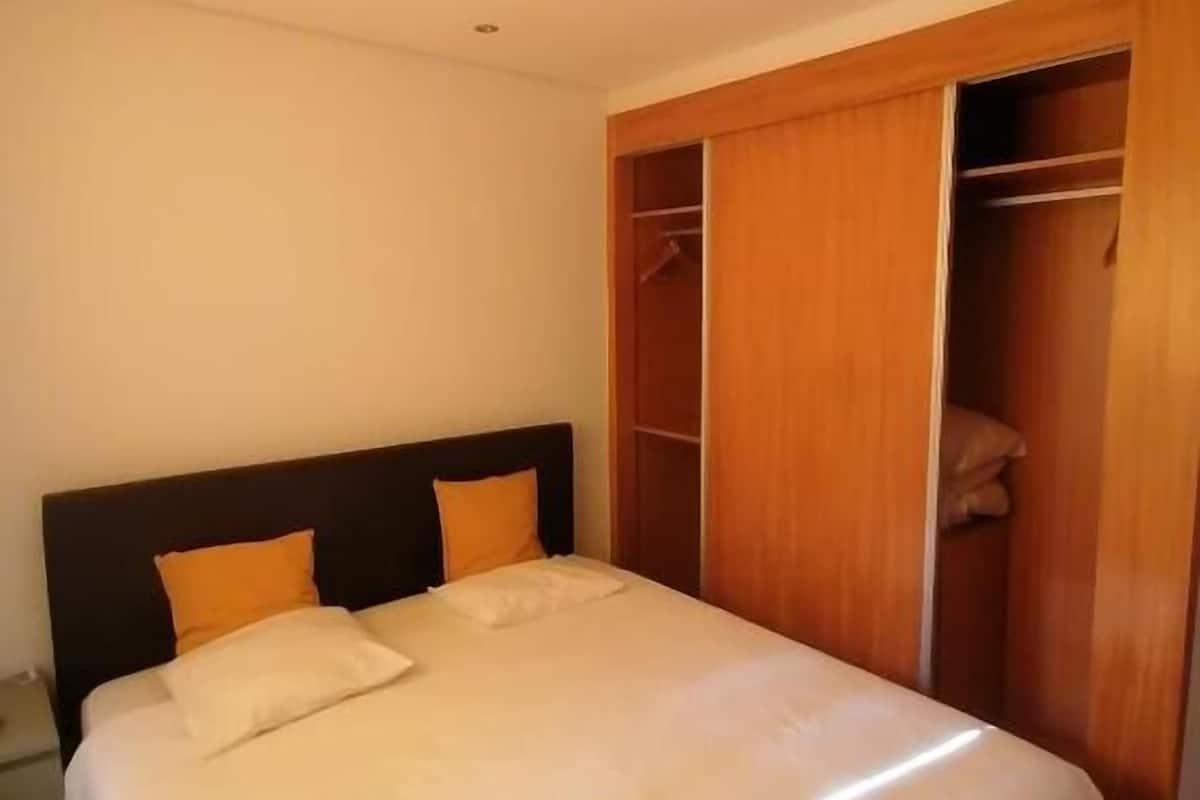 Une chambre à coucher avec un grand lit, une armoire en bois et une table de chevet.