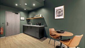 A modern kitchen with dark cabinets, a wooden countertop, and a small dining area with two chairs and a table. - Aurora Nooks - Superior Studio for 2 - free parking (Kópavogur)