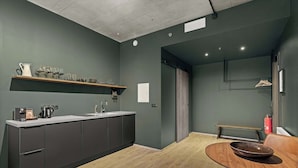 A modern kitchen with dark cabinets, a wooden countertop, and a dining area with a round table and a bowl.