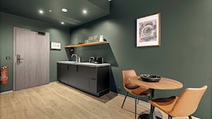 A modern kitchen with dark cabinets, a wooden countertop, and a small dining area with two chairs and a table.