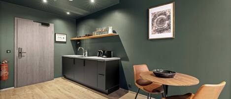 A modern kitchen with dark cabinets, a wooden countertop, and a small dining area with two chairs and a table.