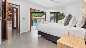 Une chambre moderne avec un grand lit, une table de chevet en bois et un ventilateur de plafond.