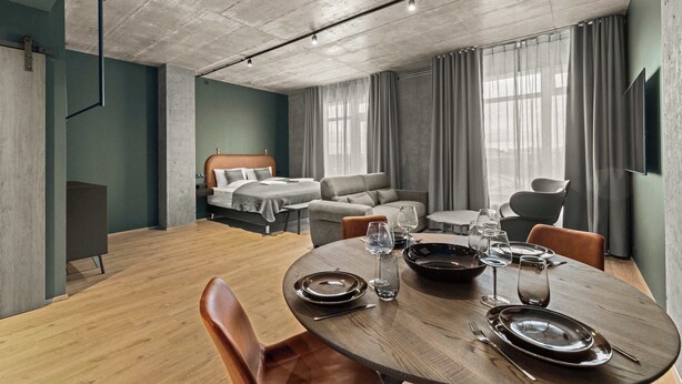 A modern hotel room with a dining area, a bed, and a TV.