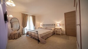 A bedroom with a bed, bedside tables, a mirror, a wardrobe, and a door.