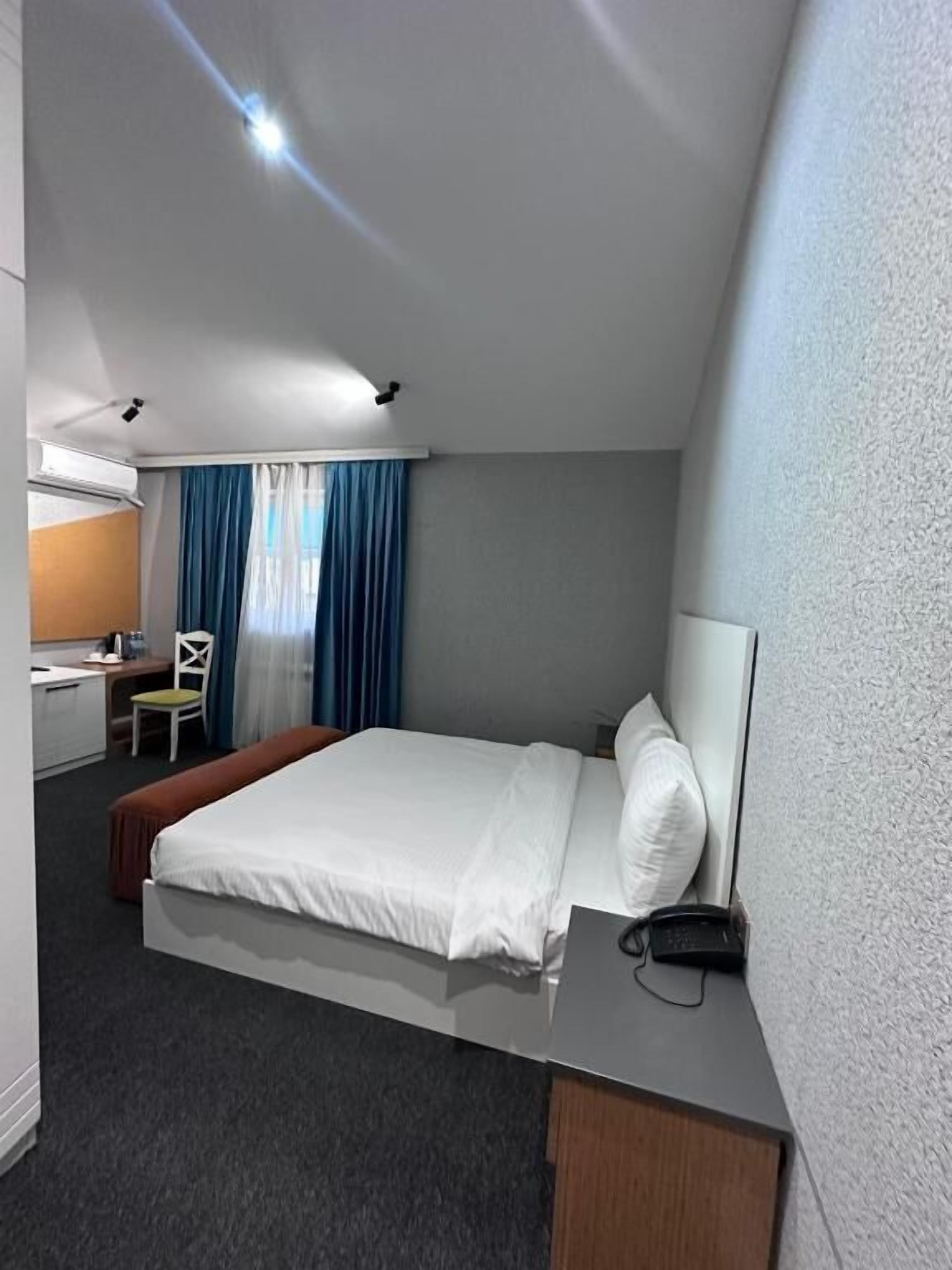 A hotel room with a bed, a desk, a chair, and a small table.