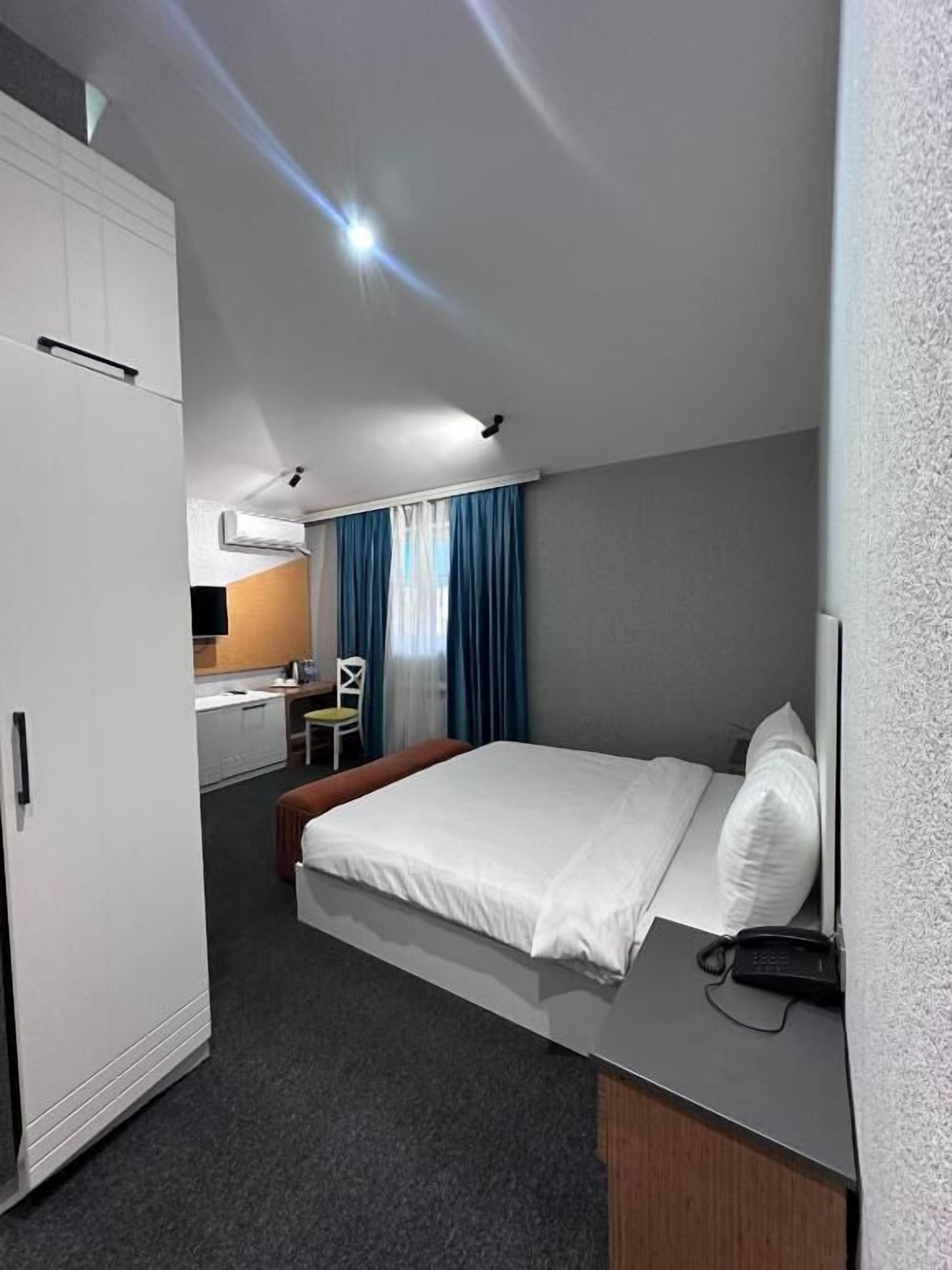 Une chambre d’hôtel avec un lit, un bureau, une chaise et une armoire.