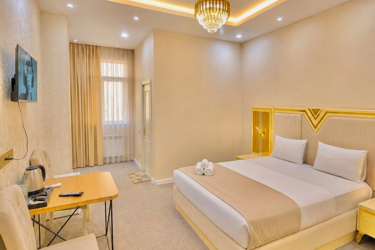 Habitación de hotel con cama, mesita de noche, silla, escritorio y televisor.