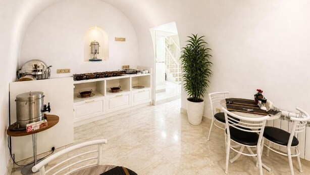 Un interior blanco con cocina, comedor y una planta en maceta.