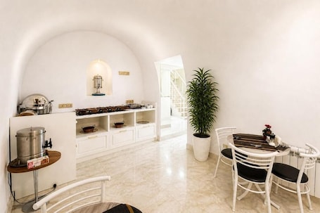 A white interior with a kitchen, dining area, and a potted plant.