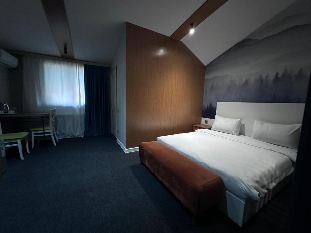 Una habitación de hotel con cama, escritorio, silla y mesita de noche.