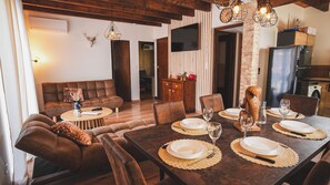 A dining area with a wooden table set for six, surrounded by brown leather sofas and chairs.