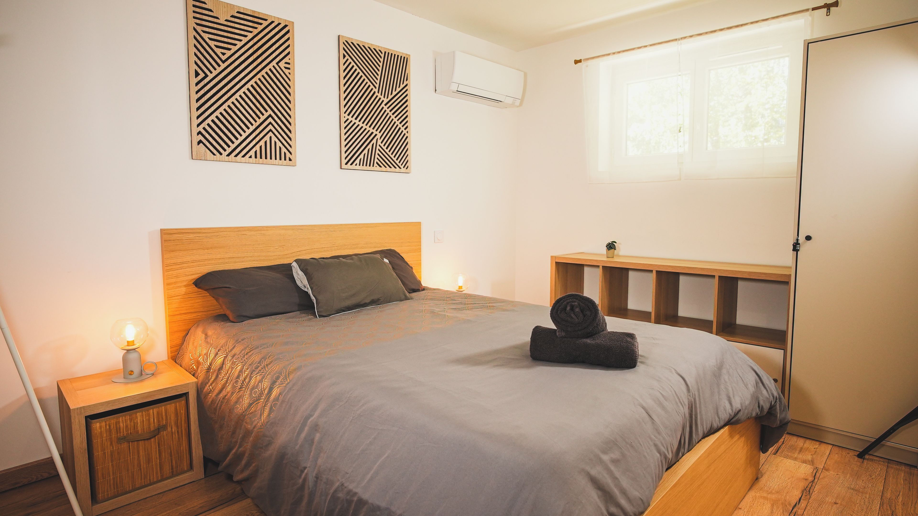 Ein Schlafzimmer mit einem Bett, Nachttischen, einem Fenster und Wanddekorationen.