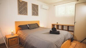 Un dormitorio con cama, mesitas de noche, ventana y adornos en la pared.