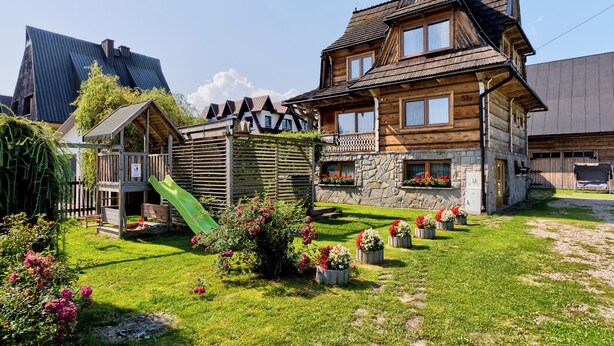 A wooden house with a stone facade, a wooden deck, and a green slide. - Tatra Wooden Apartment (Czarny Dunajec)