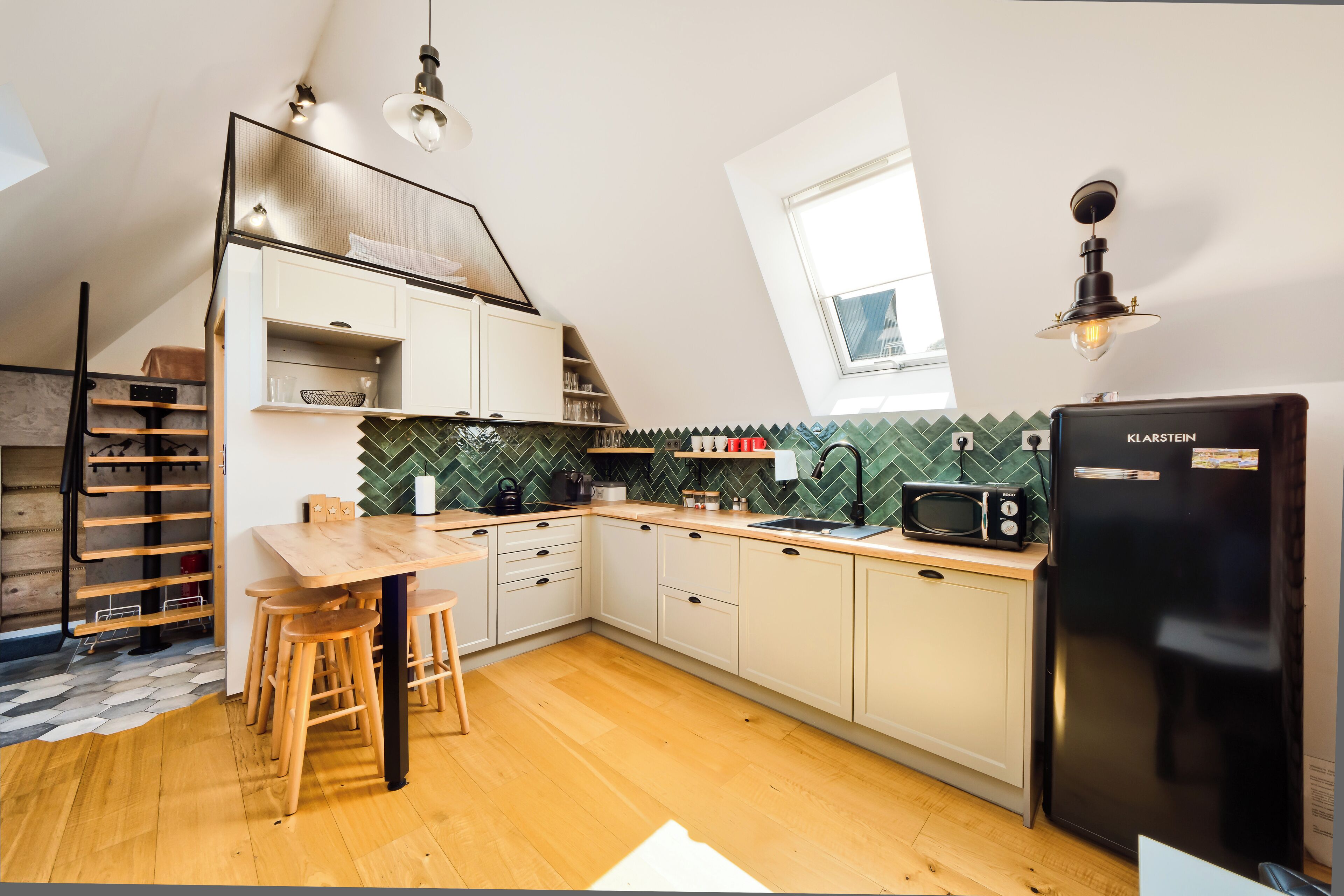 Una cocina moderna con armarios blancos, una mesa de comedor de madera y un refrigerador negro.