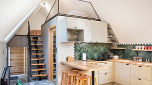 A compact kitchen with a wooden countertop, stools, and a herringbone-patterned backsplash. - Tatra Wooden Apartment (Czarny Dunajec)