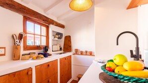 Eine Küche mit Holzausstattung, einem Fenster und einer Obstschale auf der Arbeitsfläche.