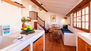 Eine Küche mit einer Holztreppe, einem Essbereich mit Tisch und Stühlen und einer kleinen Sitzecke mit einer Bank.
