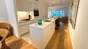 A modern kitchen with white cabinets, a central island, and a dining area with a sofa and chairs. - Apartment in Brussels Near European Parliament (Brussels)