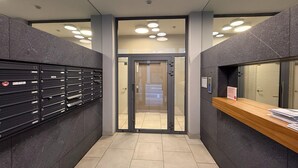 A modern elevator lobby with a metal door, a wall-mounted mailbox, and a reception desk. - Apartment in Brussels Near European Parliament (Brussels)