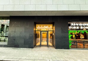 A building entrance with a glass door and a sign for 'Hawaiian Poke Bowl'.