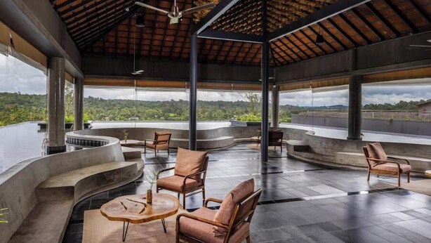 A spacious indoor area with curved seating and a view of a lush landscape. - Saptha Resort and spa (Sulthan Bathery)