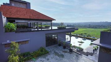 Una casa moderna con terraza en la azotea, piscina y vistas a un paisaje verde.