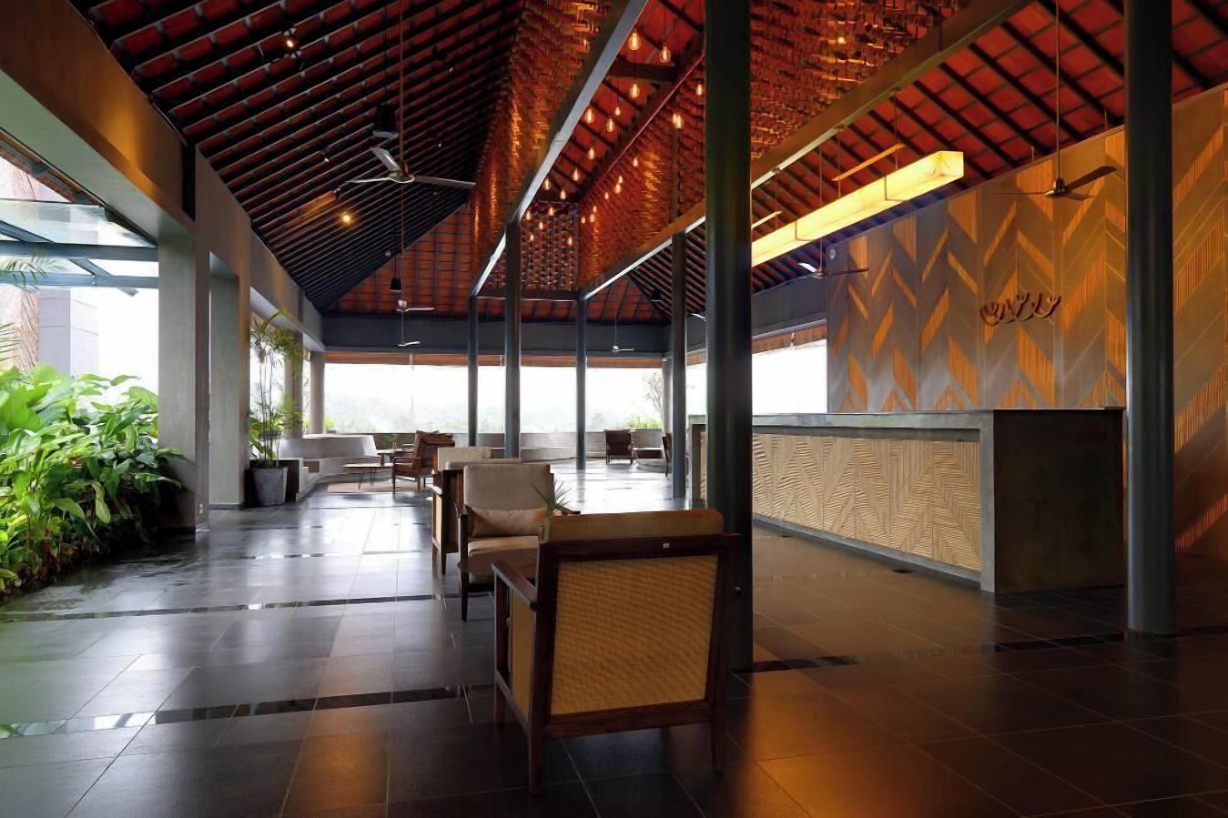 Un hall d’entrée spacieux avec un plafond haut, un mobilier moderne et un comptoir d’accueil.