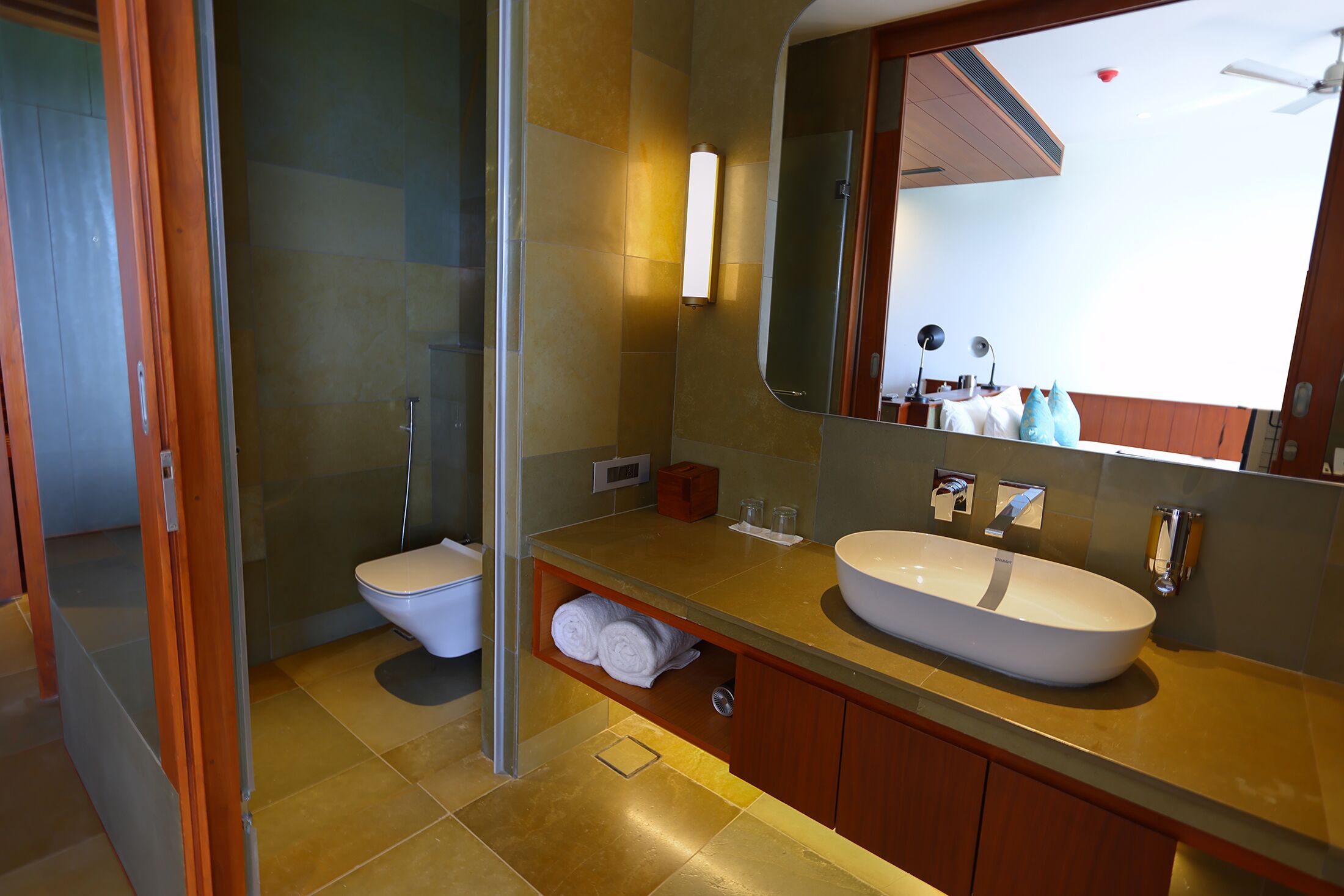 Un baño moderno con un espejo grande, un lavamanos blanco y una cabina de ducha de vidrio.