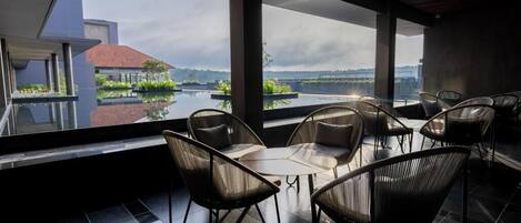 Een modern buitenzitje met uitzicht op een waterpartij en een gebouw op de achtergrond.