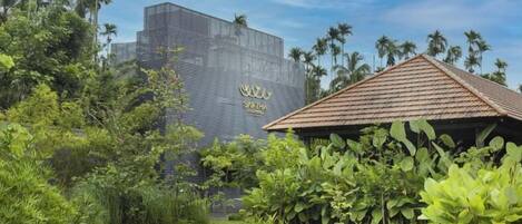 A modern building with a distinctive geometric facade and a tropical garden setting.