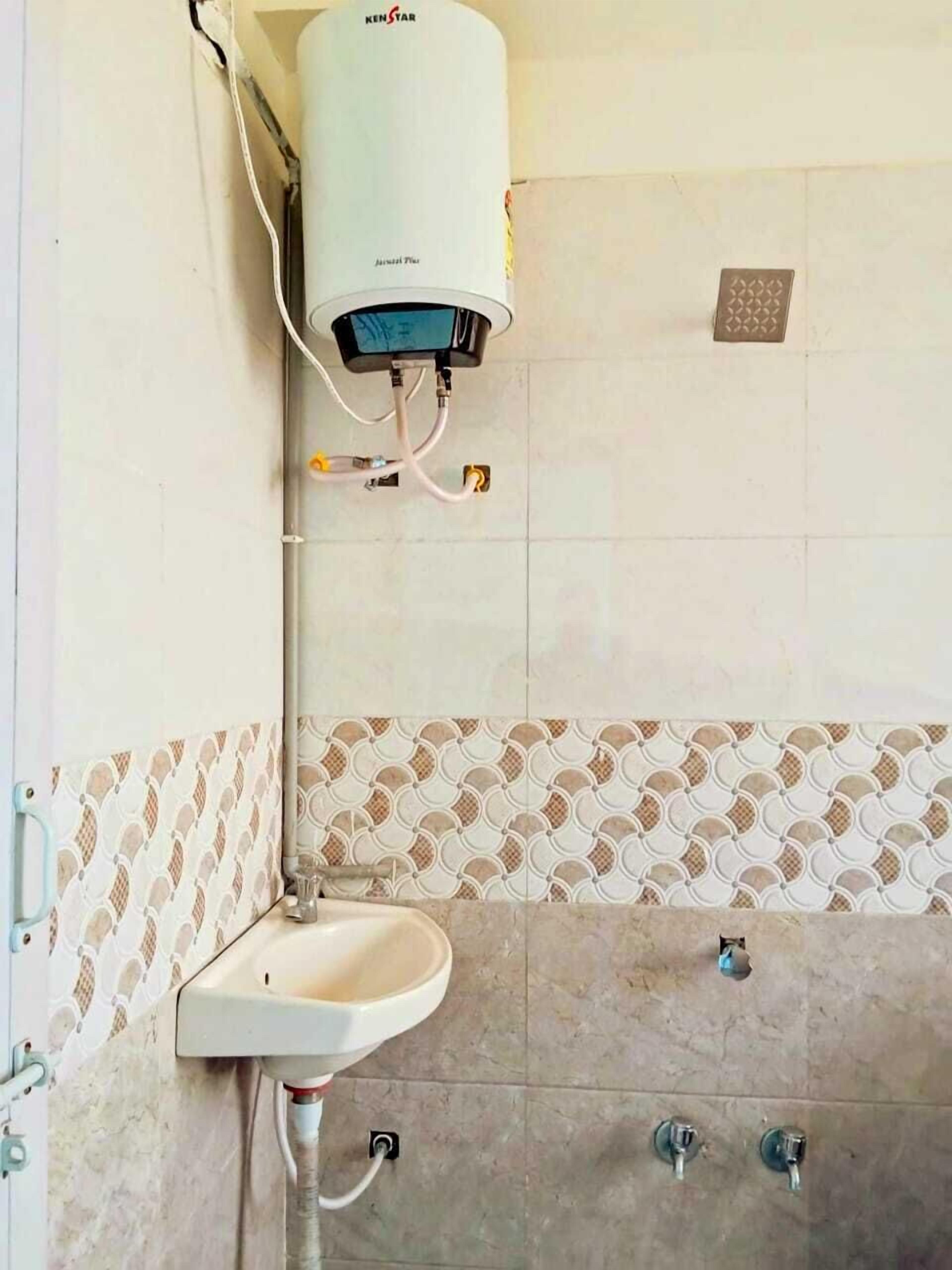 A bathroom with a white pedestal sink, a wall-mounted heater, and patterned tiles.