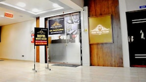 A hotel entrance with a modern design, featuring a glass door, wooden accents, and bilingual signage. - Hotel White House (Ahmedabad)