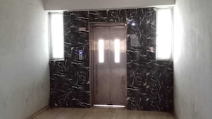 A room with a marble wall, a door, and a window. - Hotel White House (Ahmedabad)