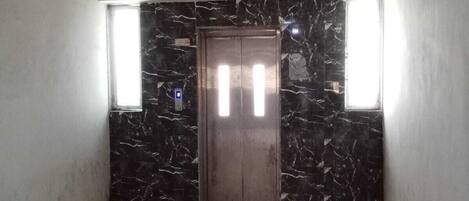 A room with a marble wall, a door, and a window.