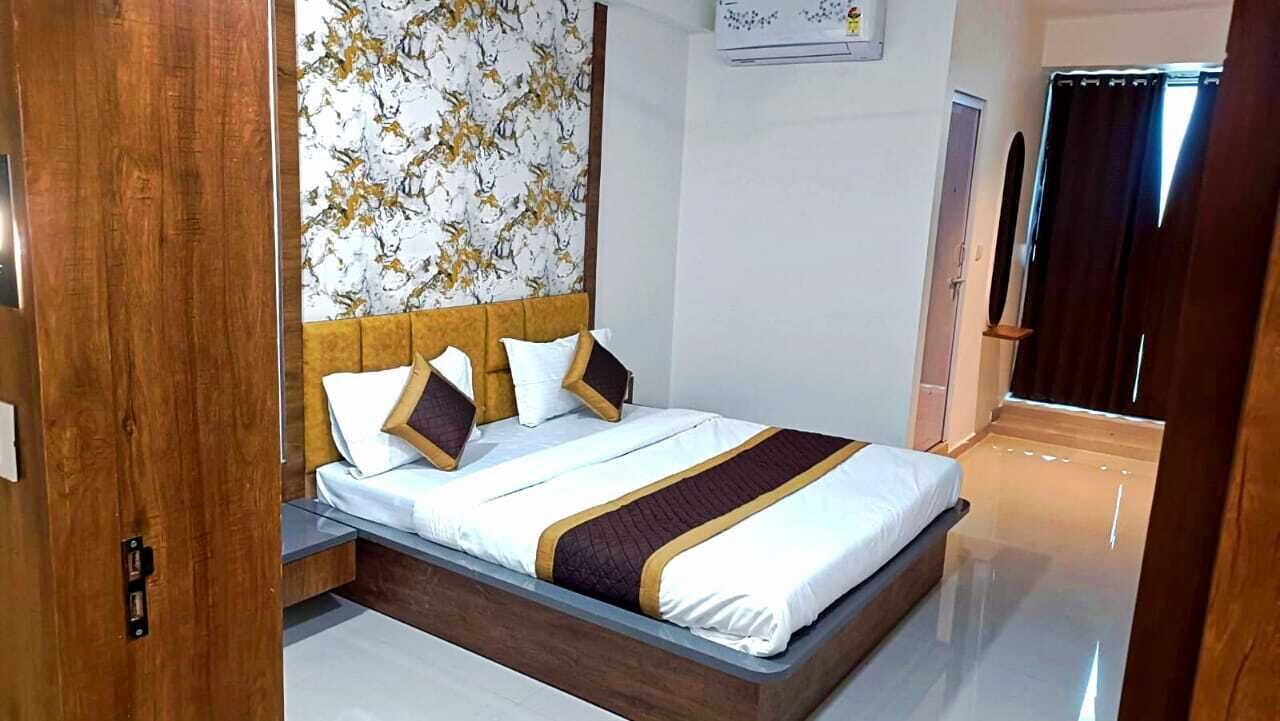 Una cama bien hecha con cabecera, un marco de puerta de madera y una pared con estampado floral.