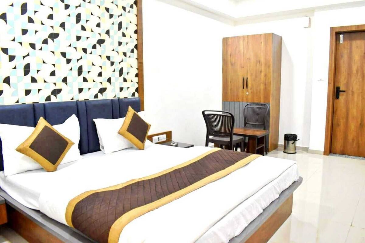 Une chambre d’hôtel comprenant un lit, un bureau, une chaise, une armoire et une poubelle.