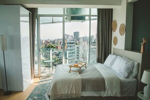 A modern hotel room with a large bed, a balcony with a view of the city, and a small table with a tray. - Chic Loft w/ AC, Walkable Area (Cuauhtémoc)