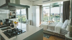 A modern hotel room with a kitchen, a large bed, a dining area, and a city view. - Chic Loft w/ AC, Walkable Area (Cuauhtémoc)