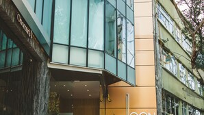 A modern building with a glass facade, a wooden staircase, and a sign reading "ICON CIBELES". - Chic Loft w/ AC, Walkable Area (Cuauhtémoc)