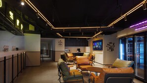 A modern lounge area with leather seating, a counter, and a television screen. - Mcsrh Hotel-Guiyang Xiaoshizi (Guiyang)