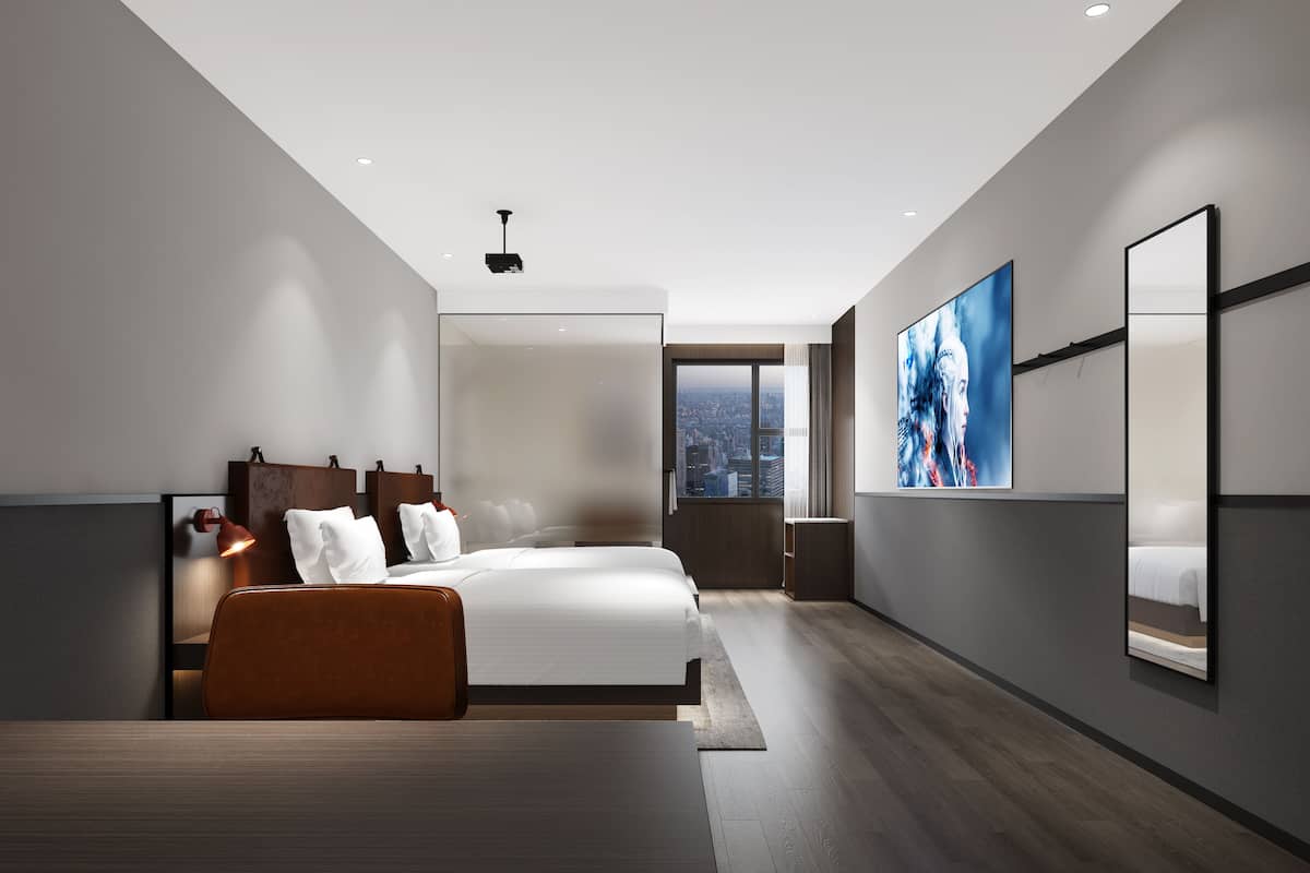 A modern hotel room with a large bed, a desk, a city view, and a large artwork on the wall.