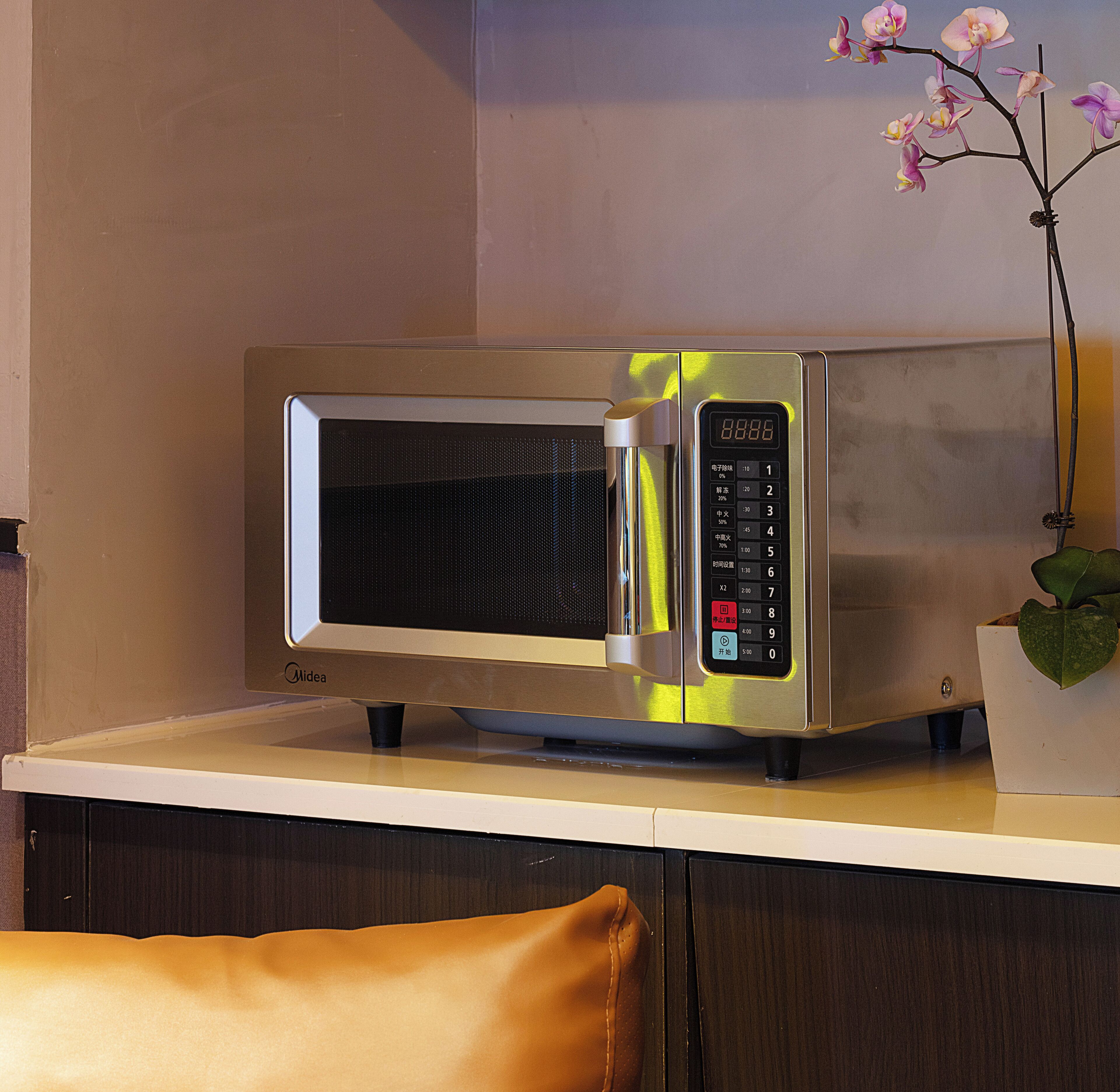 A microwave on a kitchen counter with a digital display and a control panel.