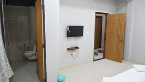 A bathroom with a toilet, shower, and a television mounted on the wall. - Hotel RRR Palace (Maheshwar)