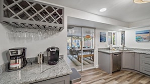 Una cocina moderna con cafetera, Keurig y copas de vino en un estante.