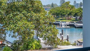 A view from a balcony overlooking a marina with boats, a dock, and a park with trees. - The Marina 308 - central Forster (Forster)