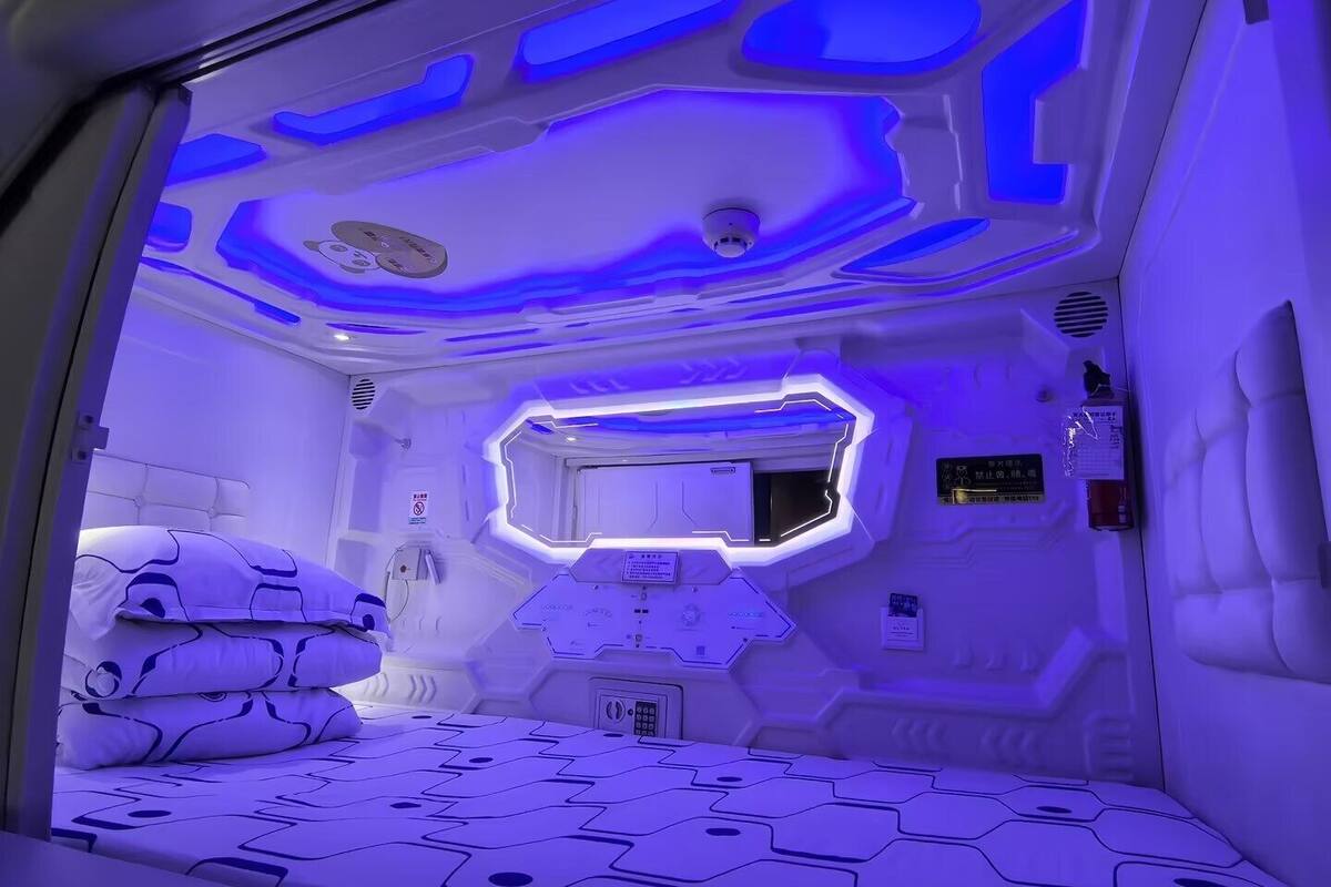 Ein futuristisches Zimmer mit einem Bett, Bedienfeldern und einem digitalen Bildschirm.