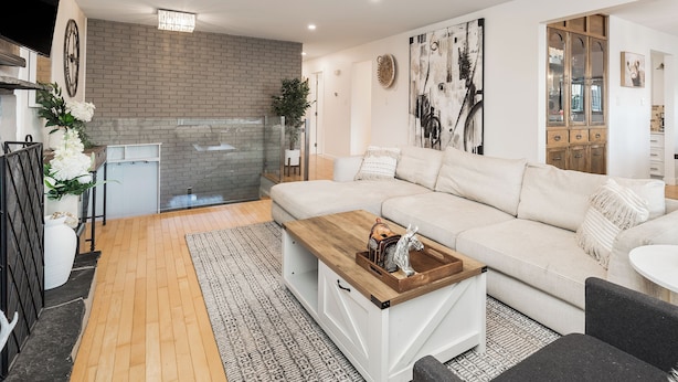 Un salon moderne avec un canapé d’angle, une table basse en bois et une cheminée.